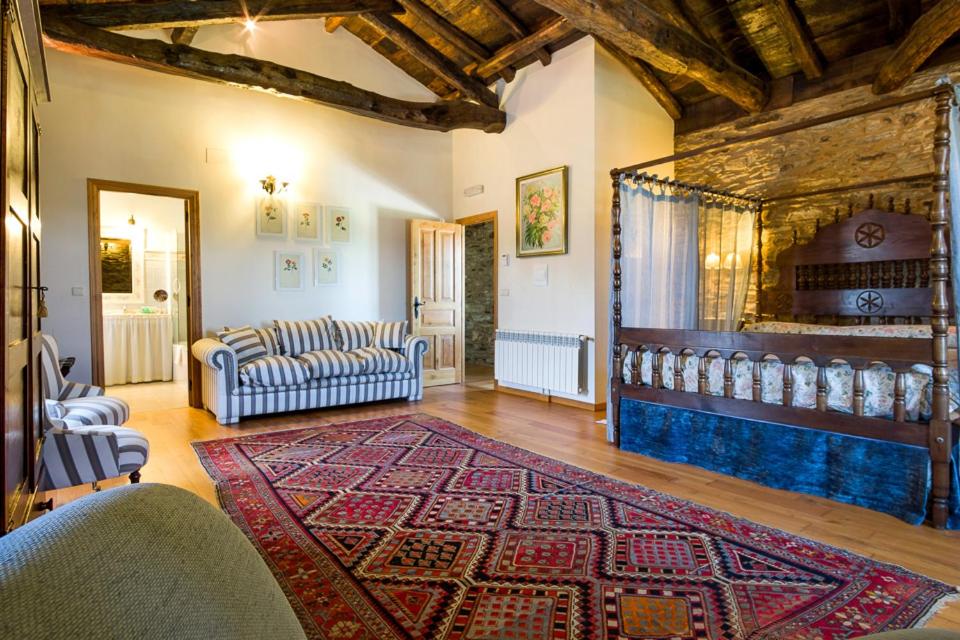 Habitación del Pazo Santa María con cama con dosel, muros de piedra y techo de madera